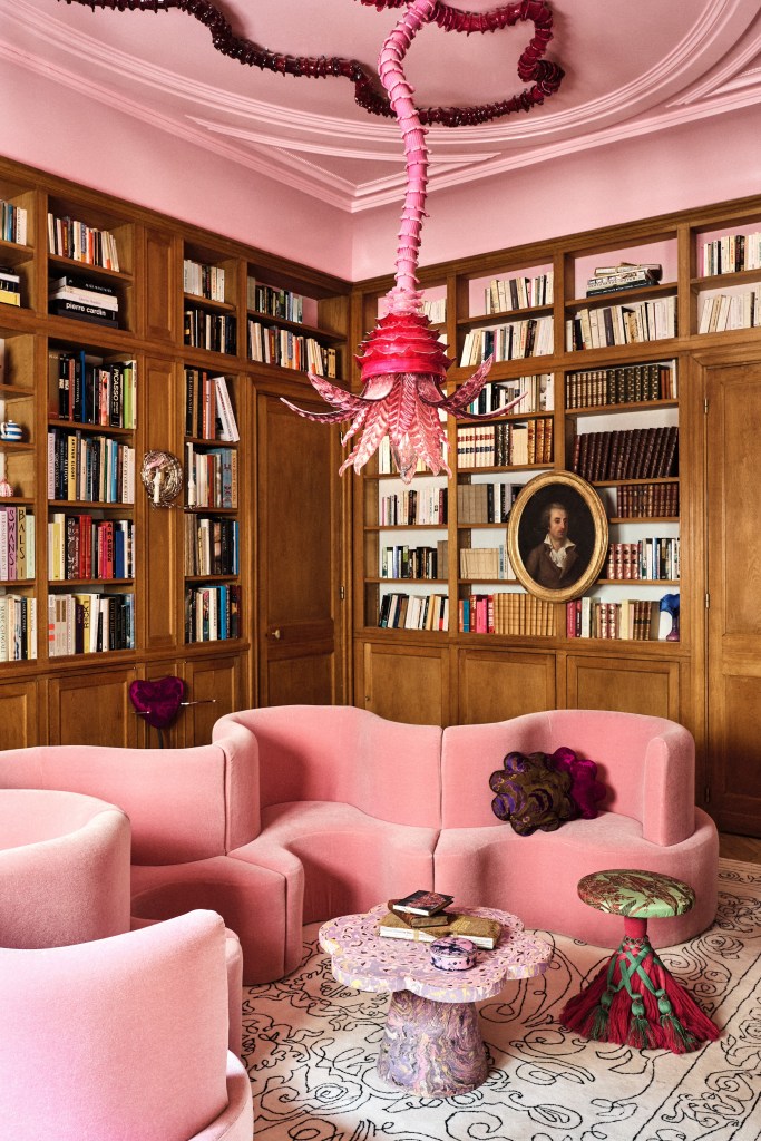 curvy pink sofa in library room with pink chandelier