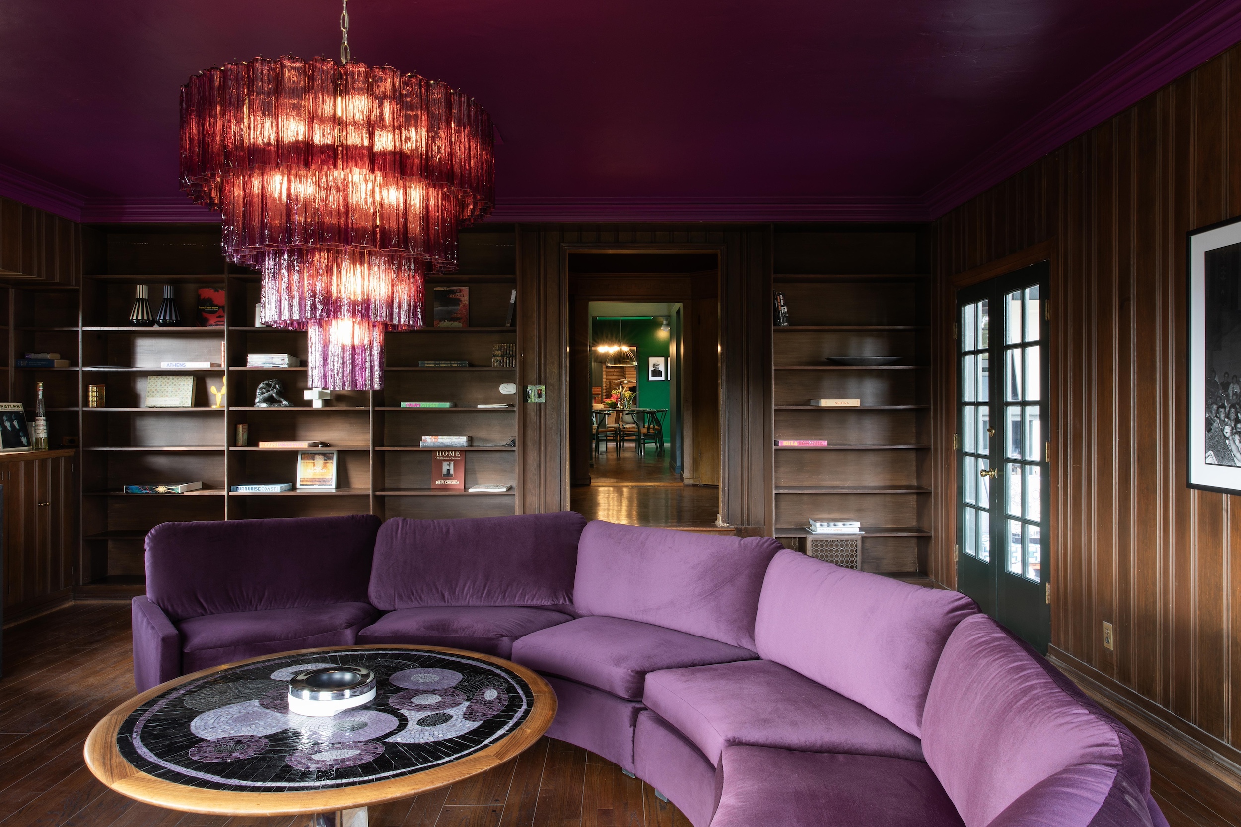 curved purple sofa in wood paneled room with bookshelves