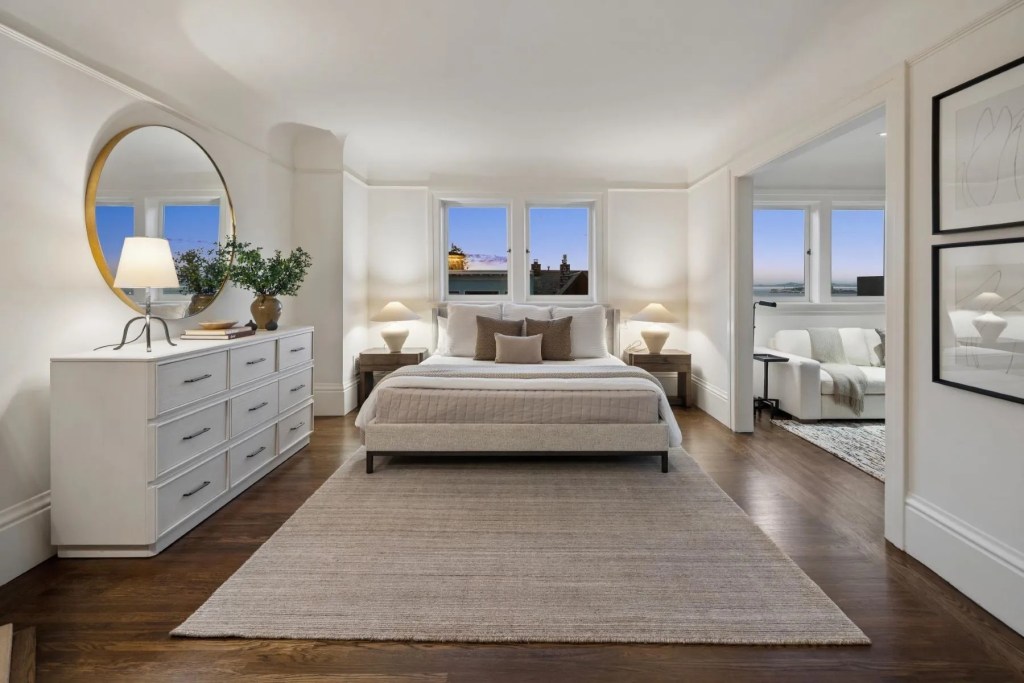 primary bedroom suite with white furniture and sitting room 