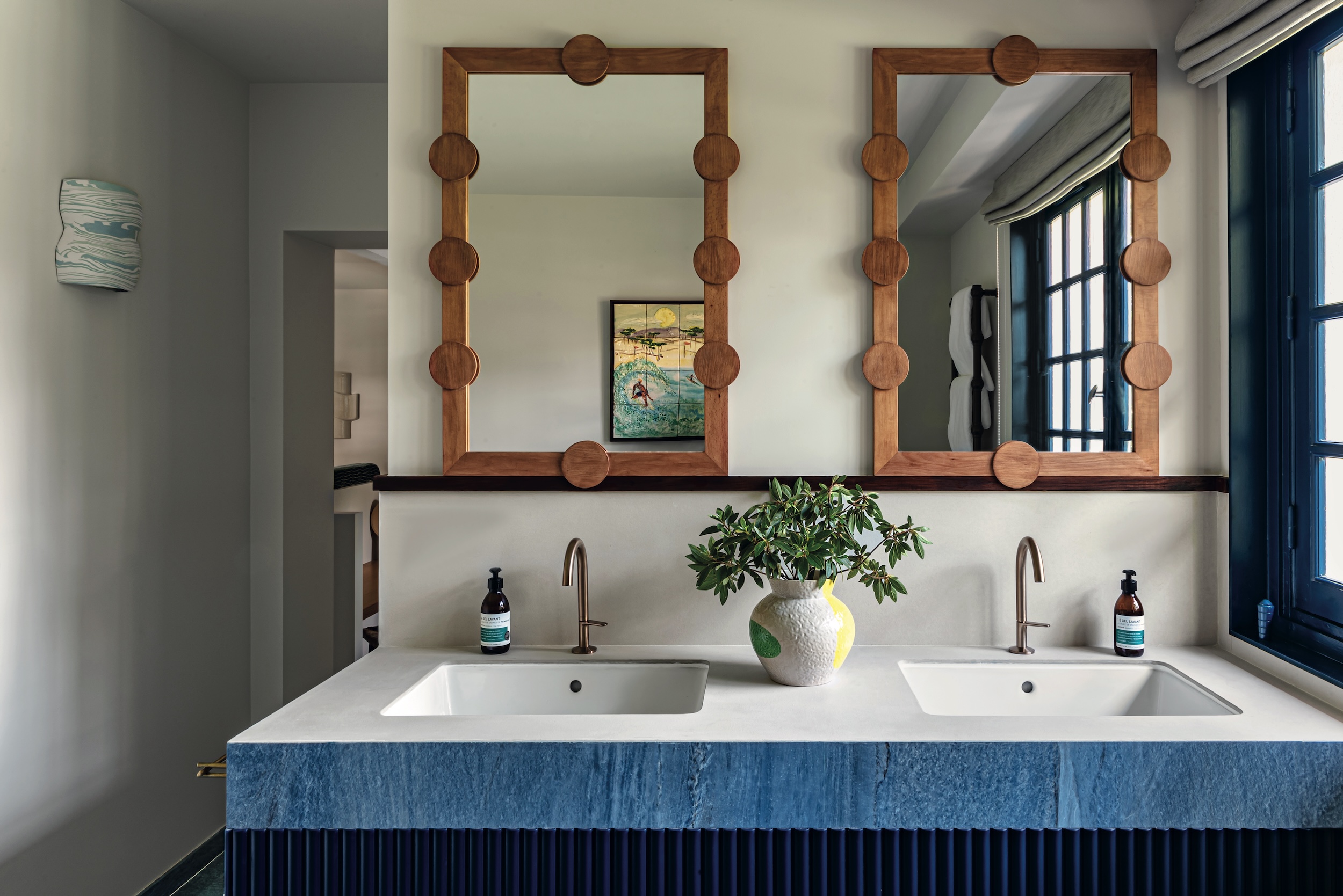 double vanity bathroom with wood-framed mirrors and white counters with a blue marble facade