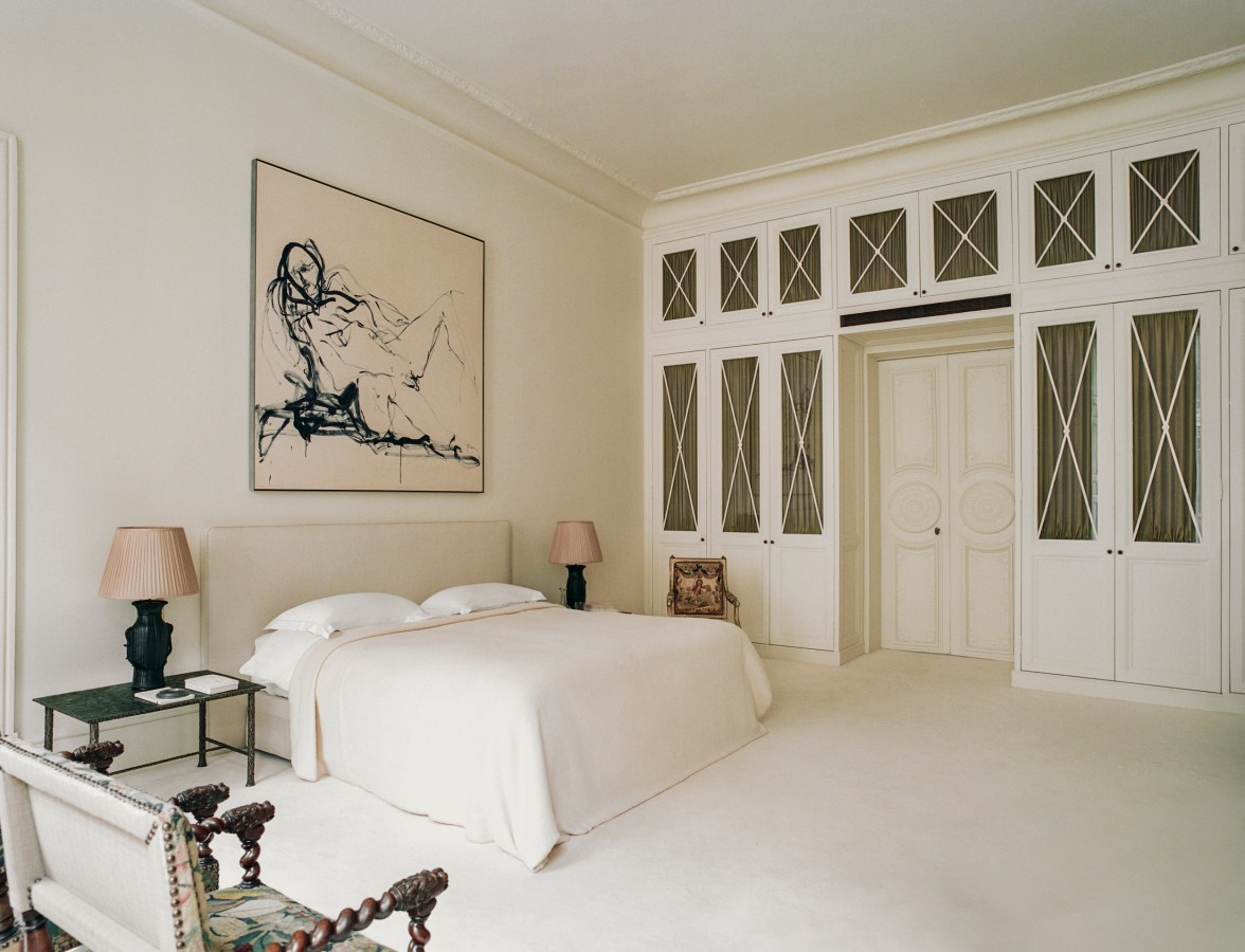 white bedroom with art on walls and french doors