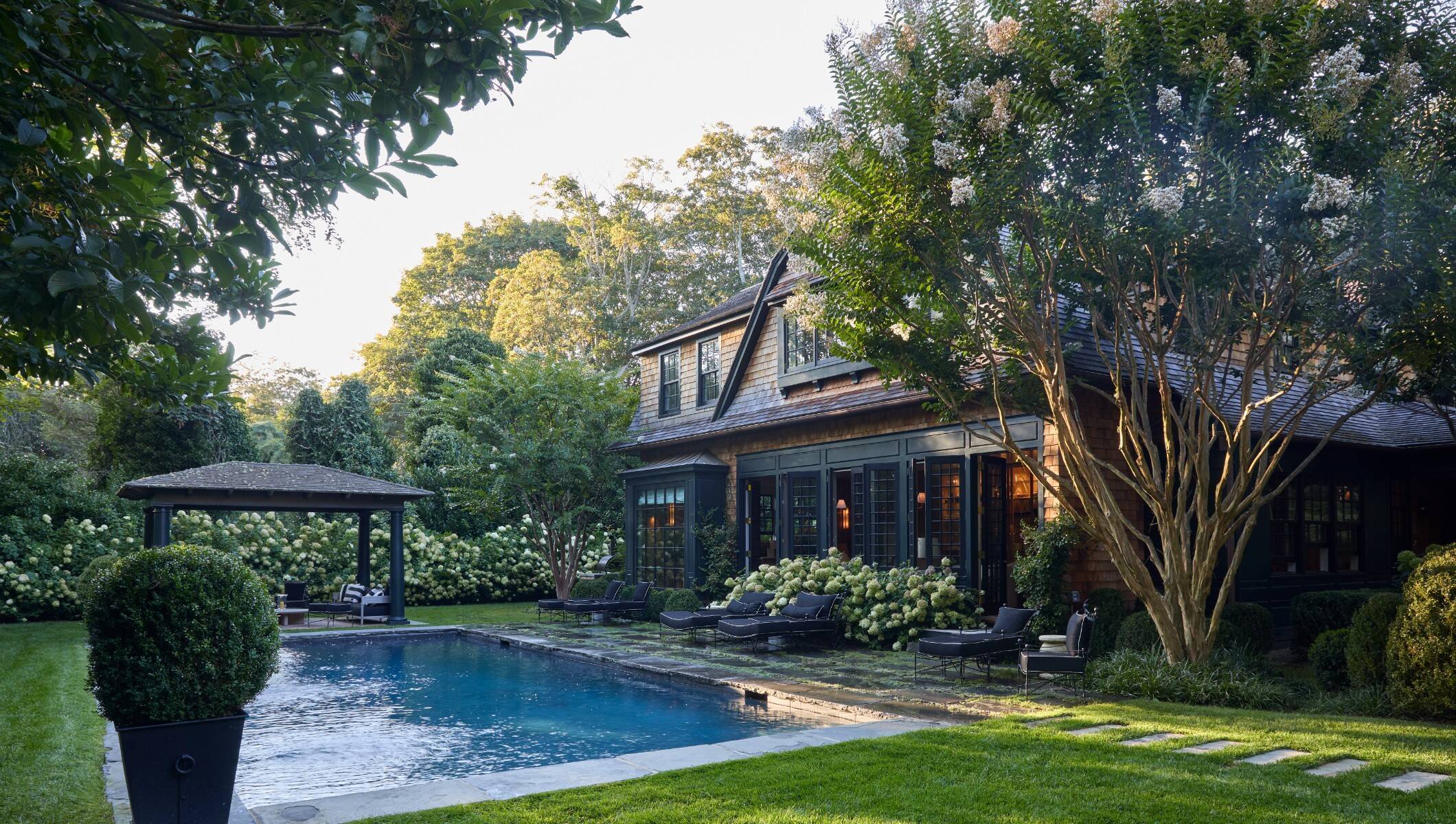 Back of East Hampton home with pool, pergola, and mature landscaping 