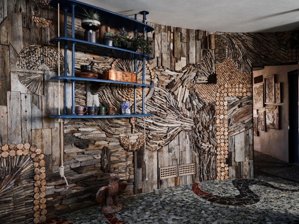 wall with driftwood mosaic and bespoke blue shelving 