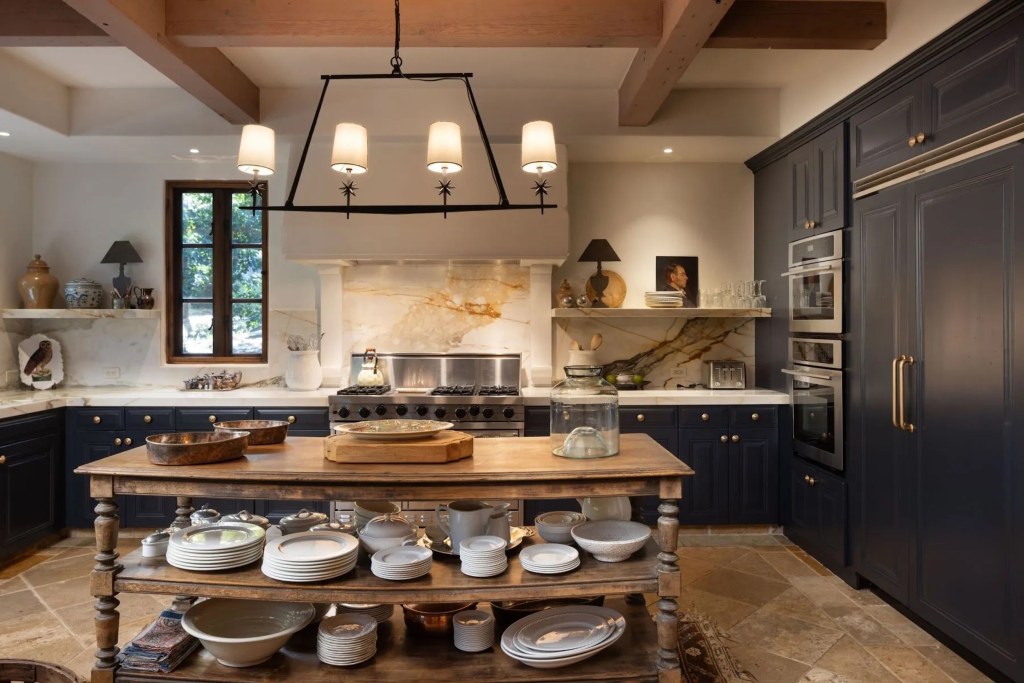 kitchen with black cabinetry, white marble countertops, and floating wood island 