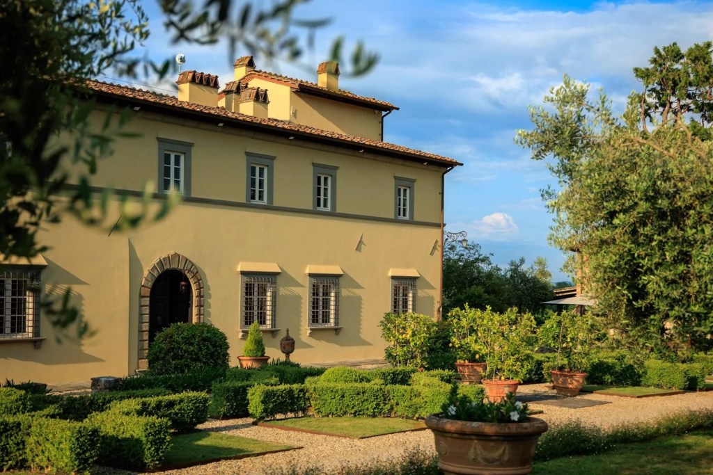 exterior of yellow villa in Tuscan countryside with landscaping 