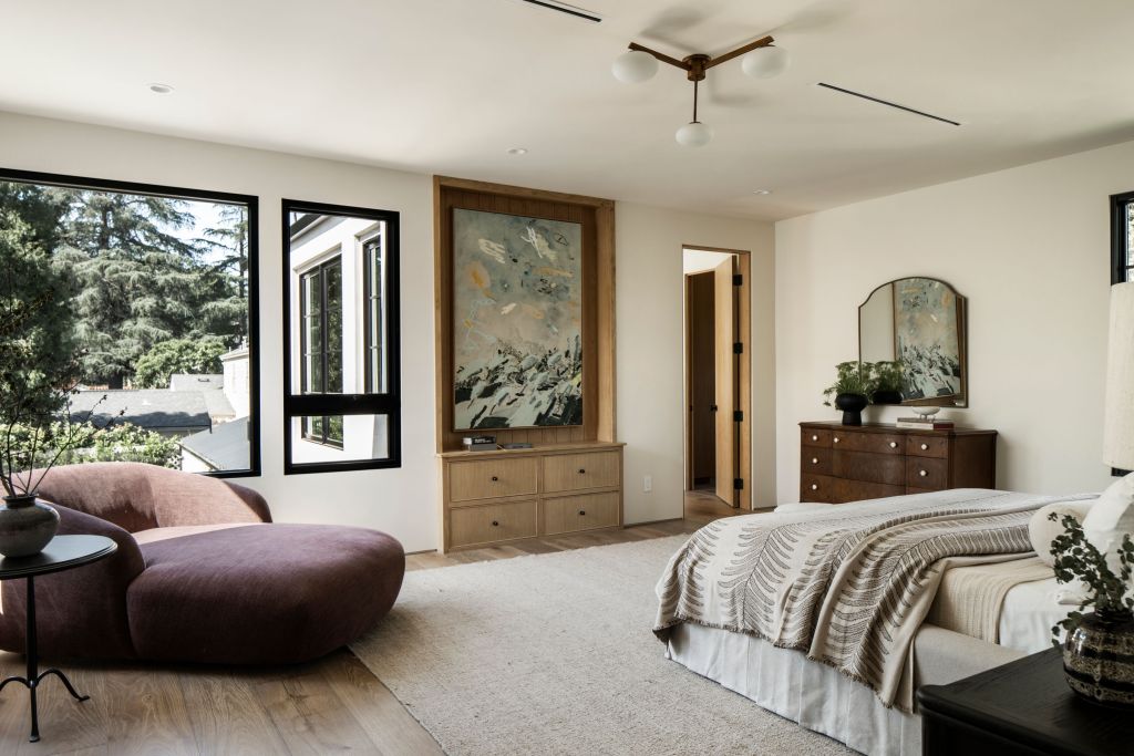 primary suite with grey bedding and lounge chair