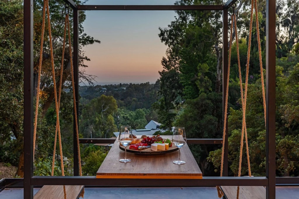 outdoor patio table with swing seating overlooking a sunset
