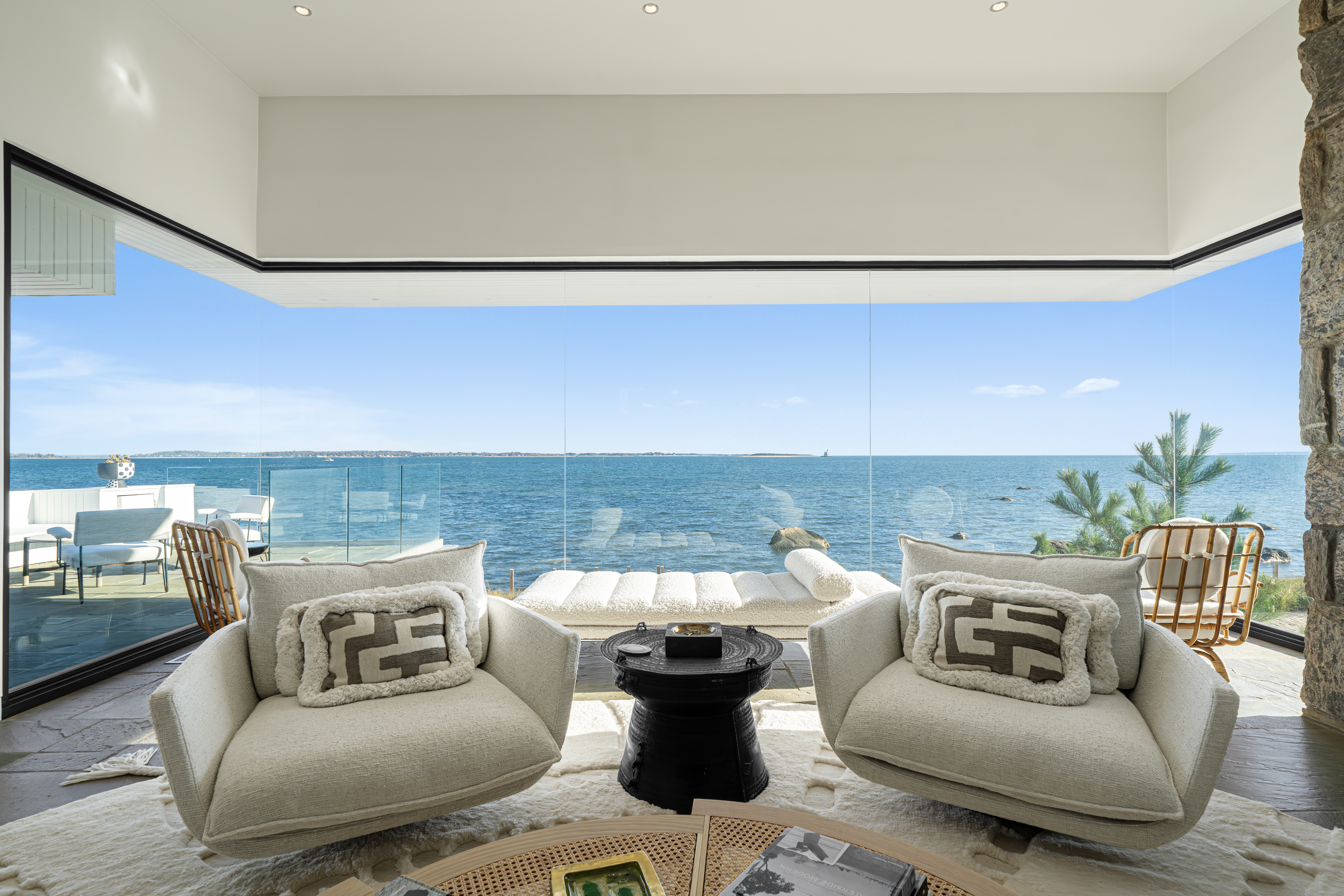 glass-walled room with seating and water views in Shelter Island, New York home