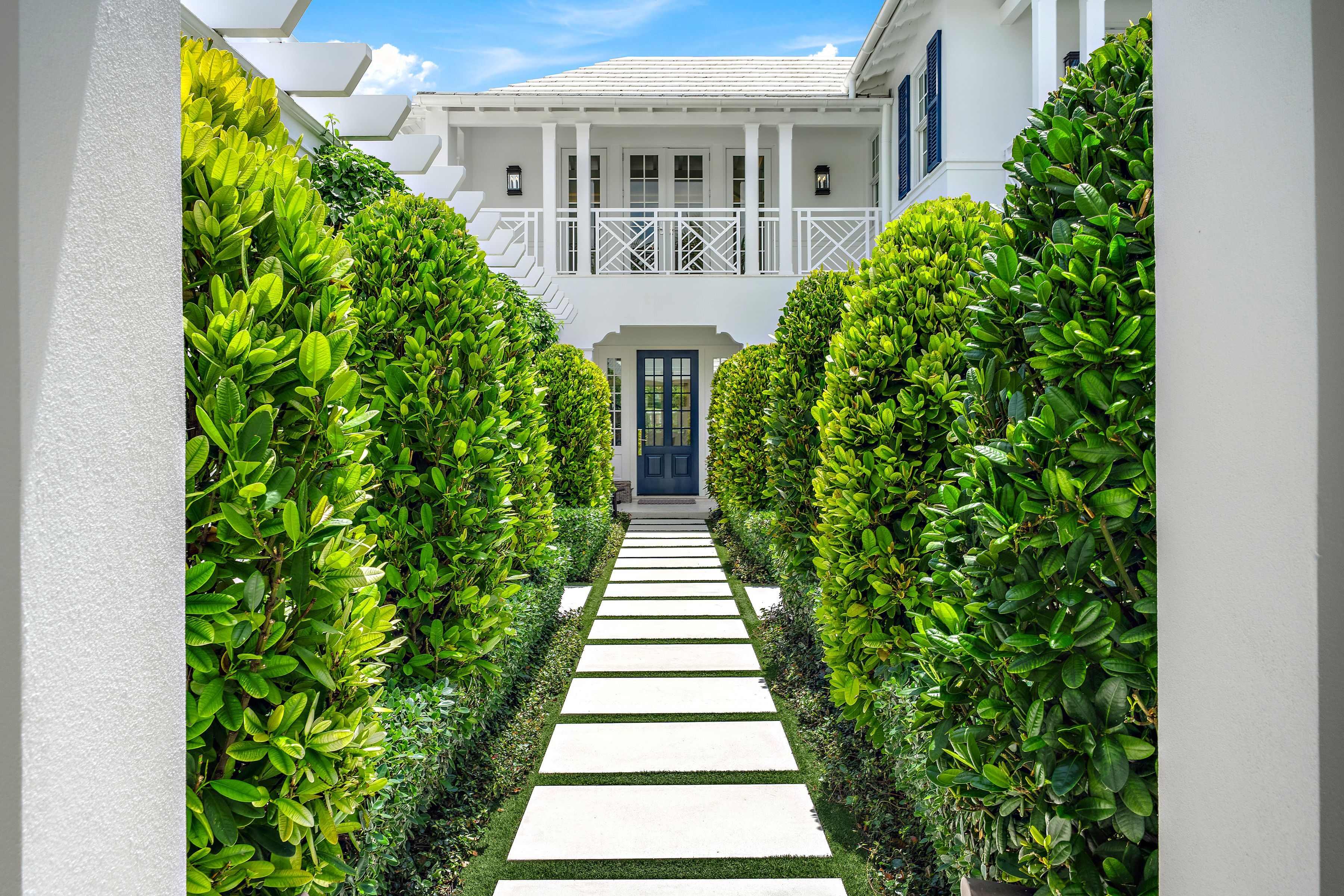 front doorway path lined with shrubs in Palm Beach home
