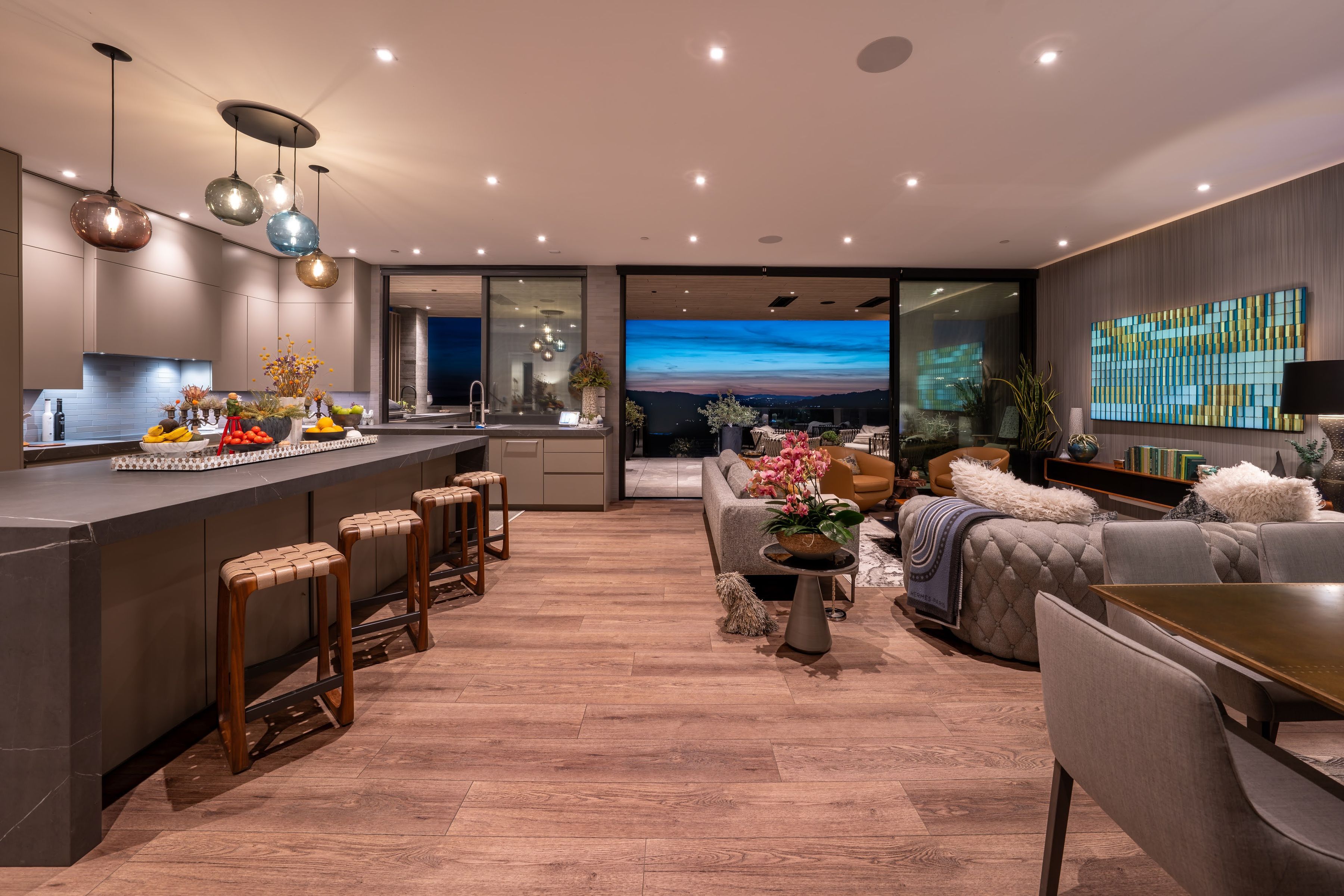 great room with modern furniture and kitchen opening to outdoors through floor-to-ceiling windows