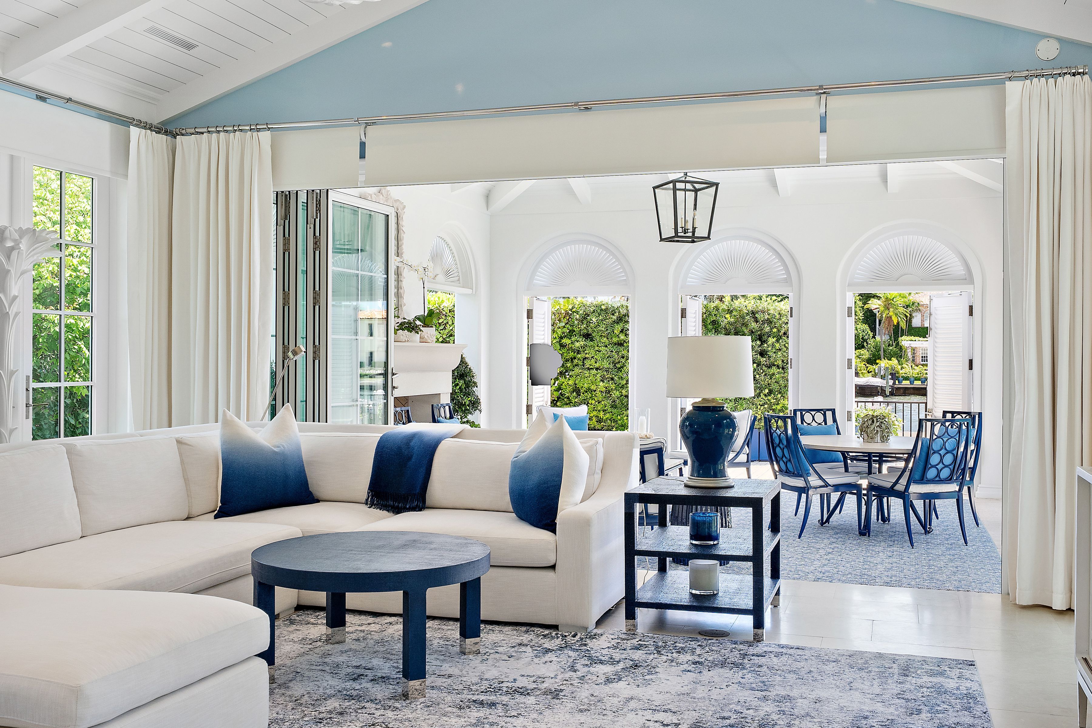 Living room in Palm Beach home with folding floor-to-ceiling windows opening to covered loggia