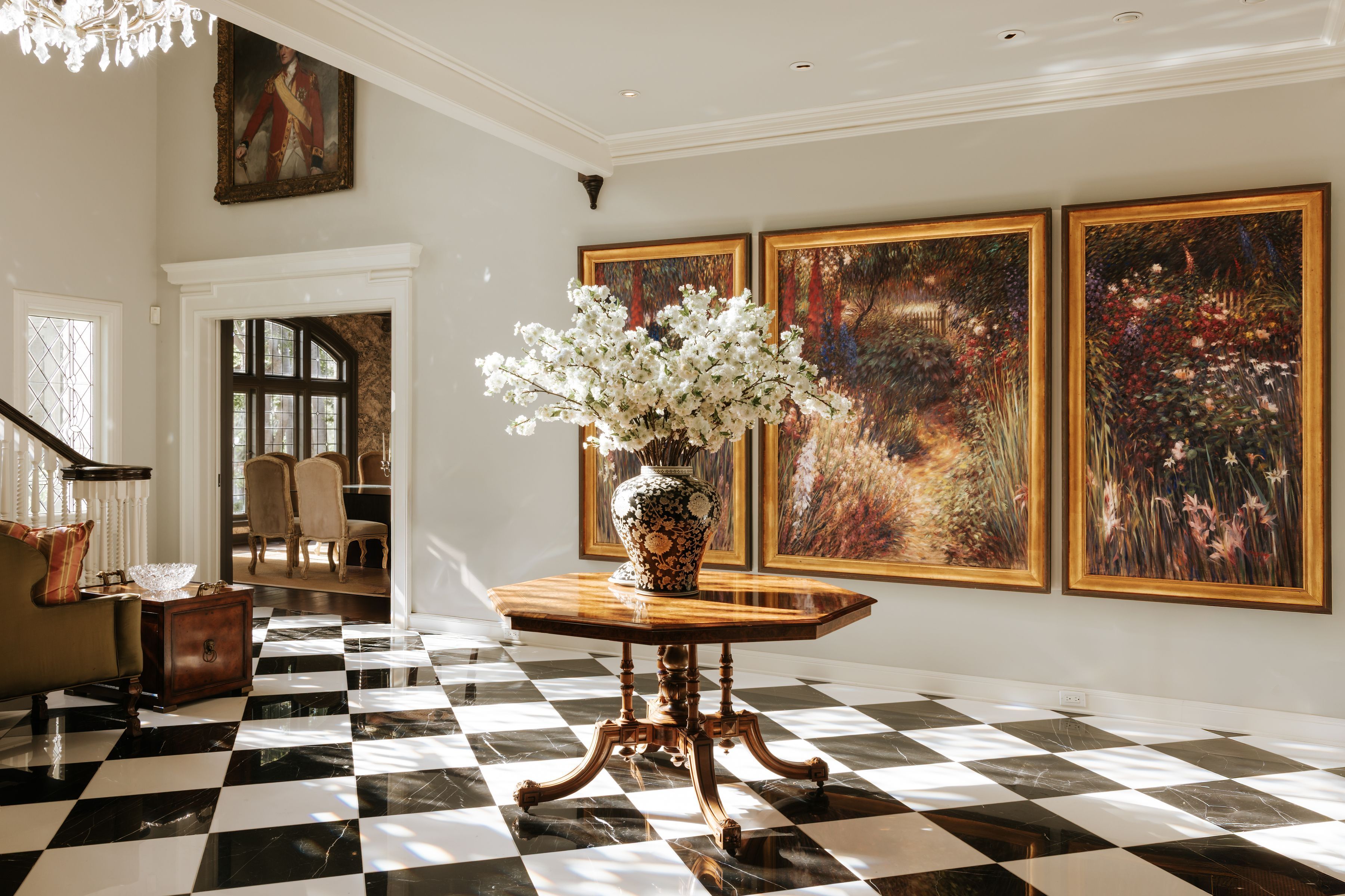 light-filled entryway with contrasting marble floors and three paintings on the wall