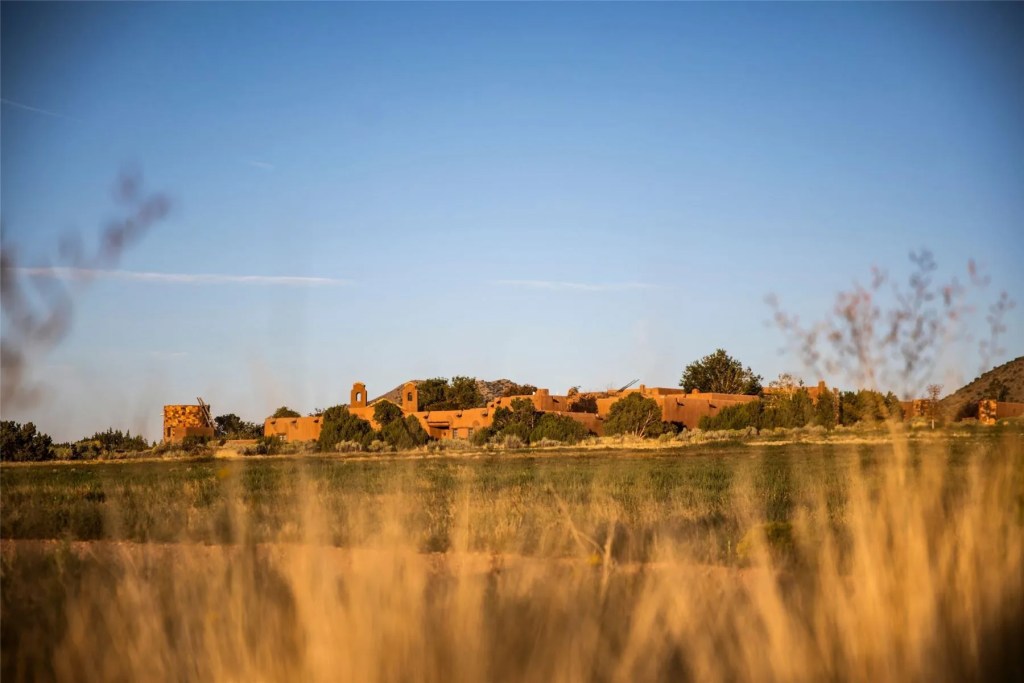 Expansive southwestern estate in Santa Fe, New Mexico, viewed from a distance at sunset.