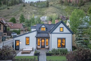 White Circa 1900 home in Telluride, Colorado with other house visible on the hillside behind the house.