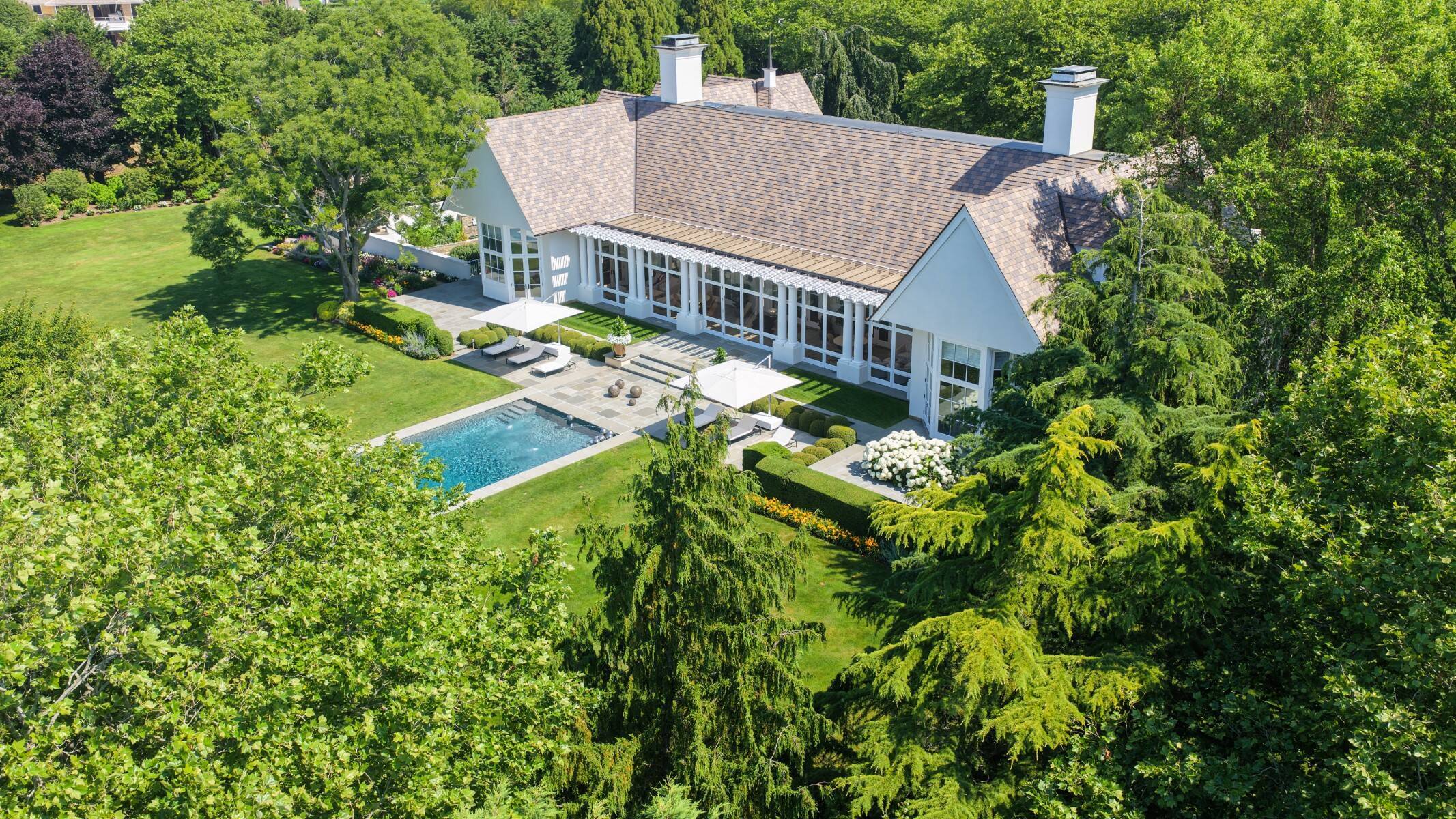 exterior of white Hamptons home with pool and lush landscaping in the Fordune Estate community