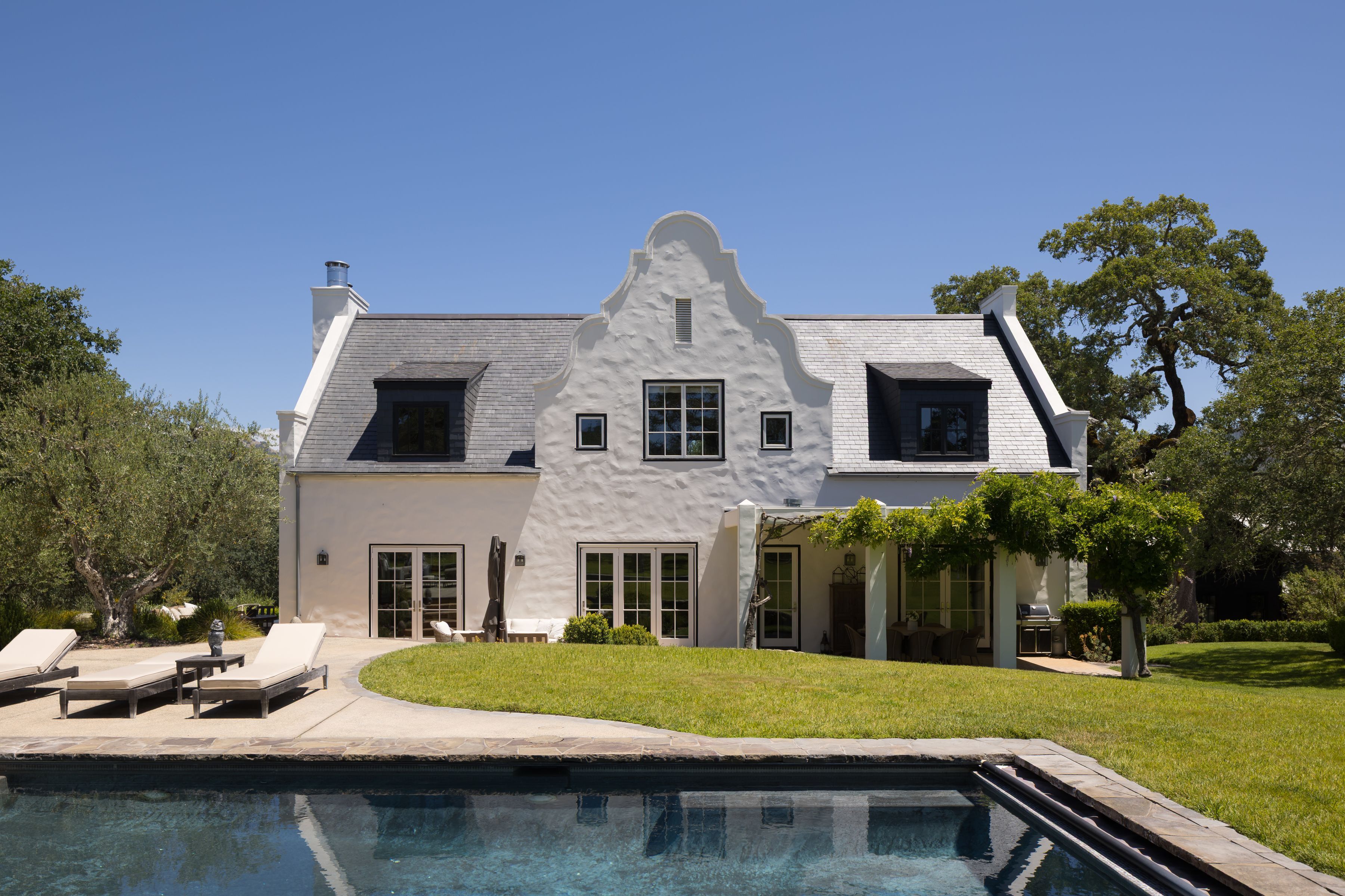 back exterior of Cape Dutch-style home in California wine country with pool deck and covered terrace