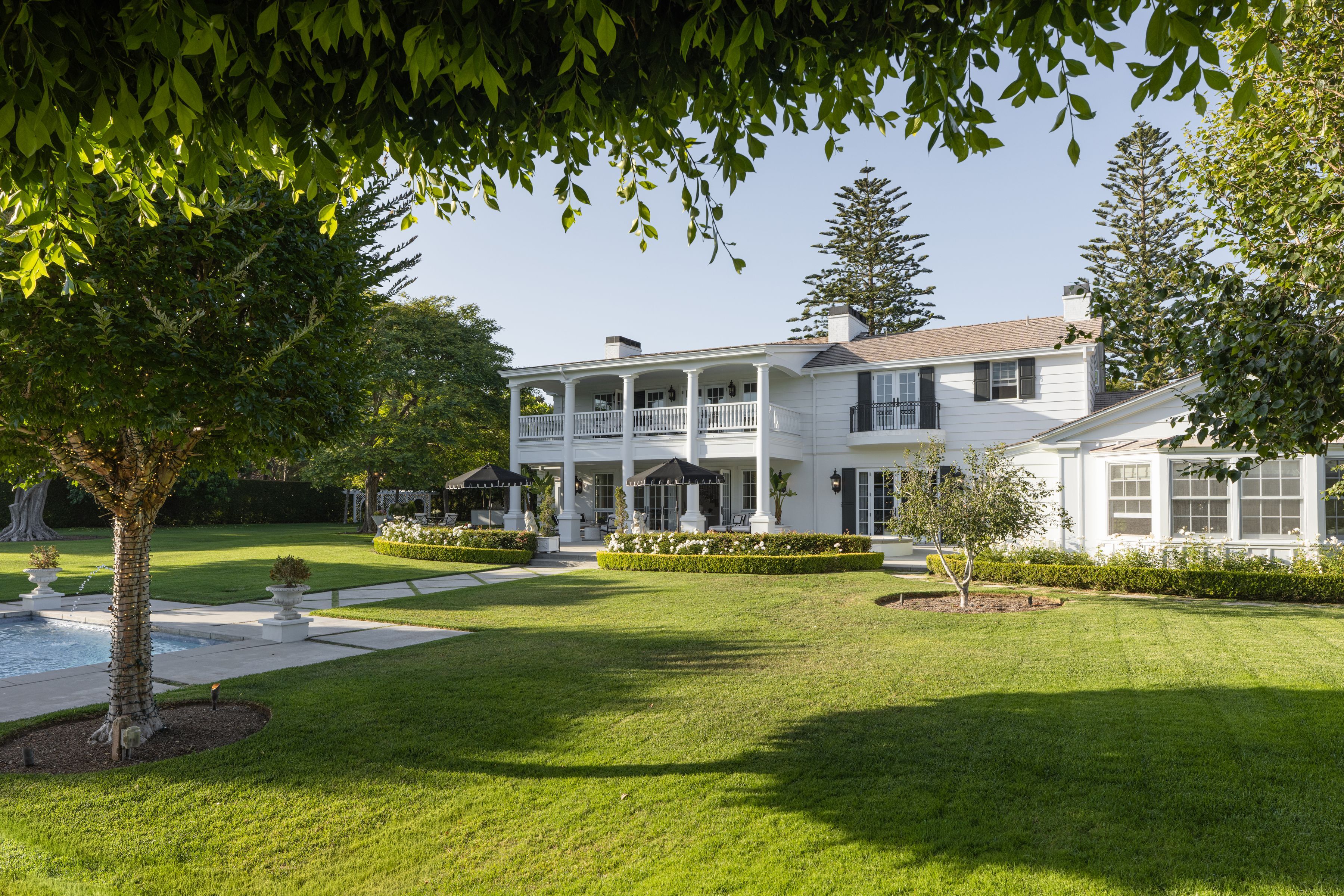 back exterior of Four Oaks estate with pool terrace and manicured landscaping