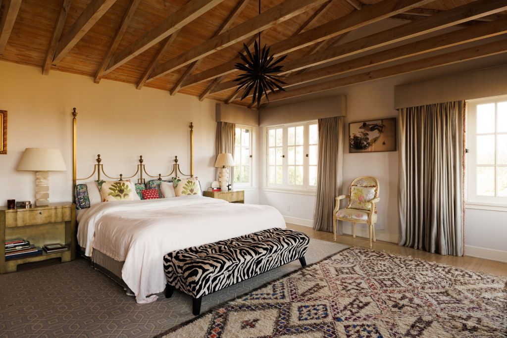 primary bedroom with vaulted ceilings, gold and wood accents and zebra print bench