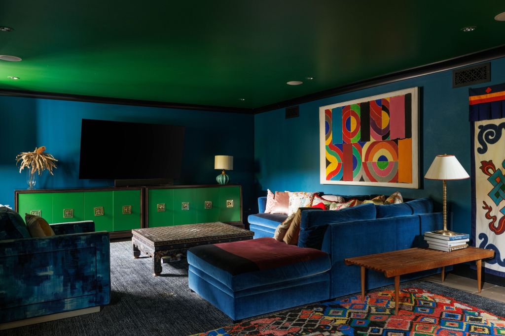 blue and green jewel toned viewing room with colorful art on walls