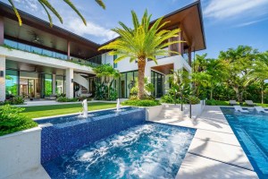 Luxury modern residence surrounded by lush palm trees, showcasing a resort-style pool and spa, outdoor living spaces, and landscaped tropical gardens. Coral gables, Florida.