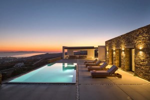 Patio and pool at sunset with ocean in the background at a home in Tinos, Greece.