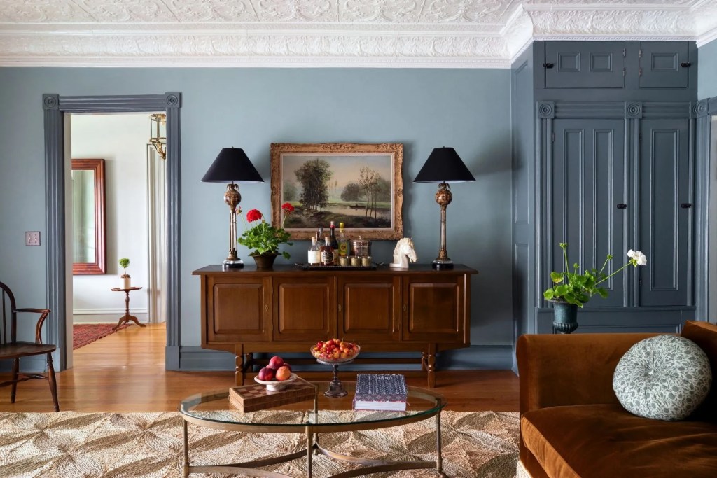 Navy blue sitting room in Hudson Valley home with brown furniture accents