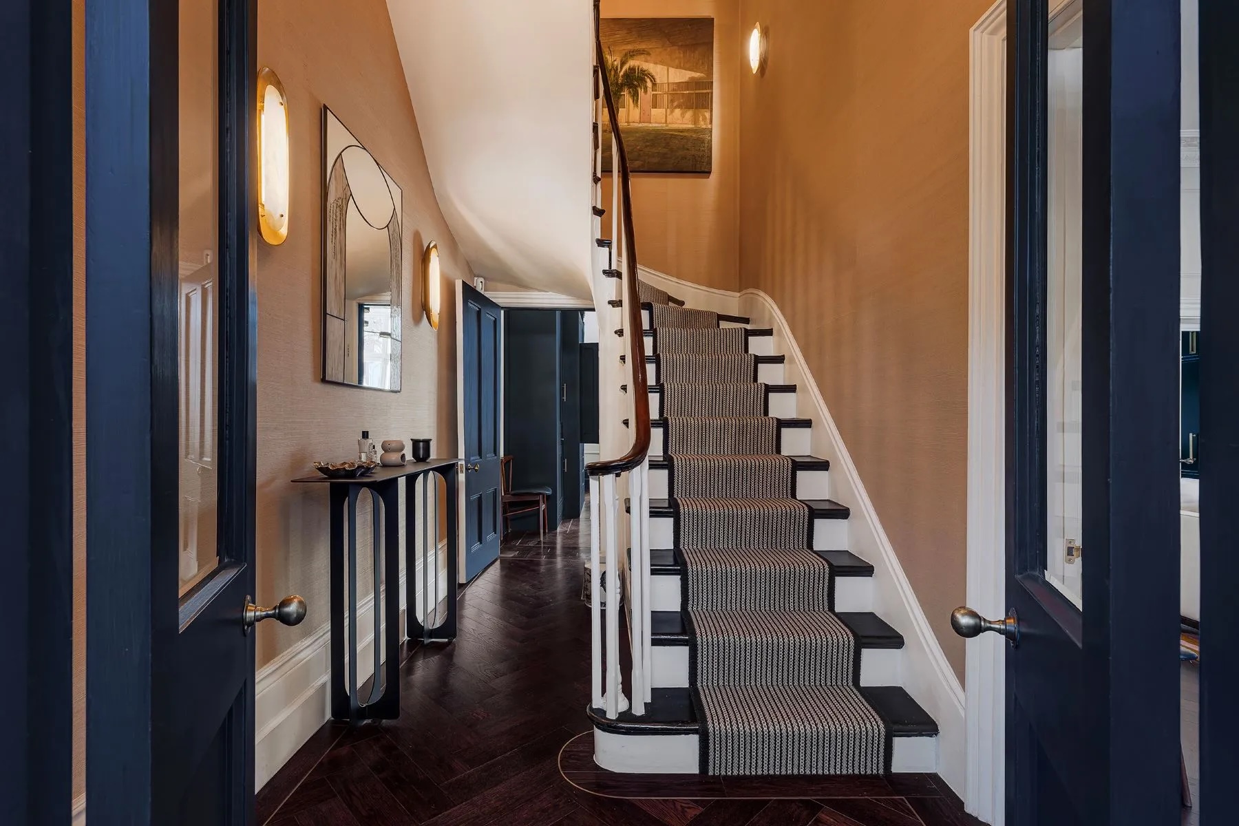 Foyer in Notting Hill home with staircase and navy blue accent doors