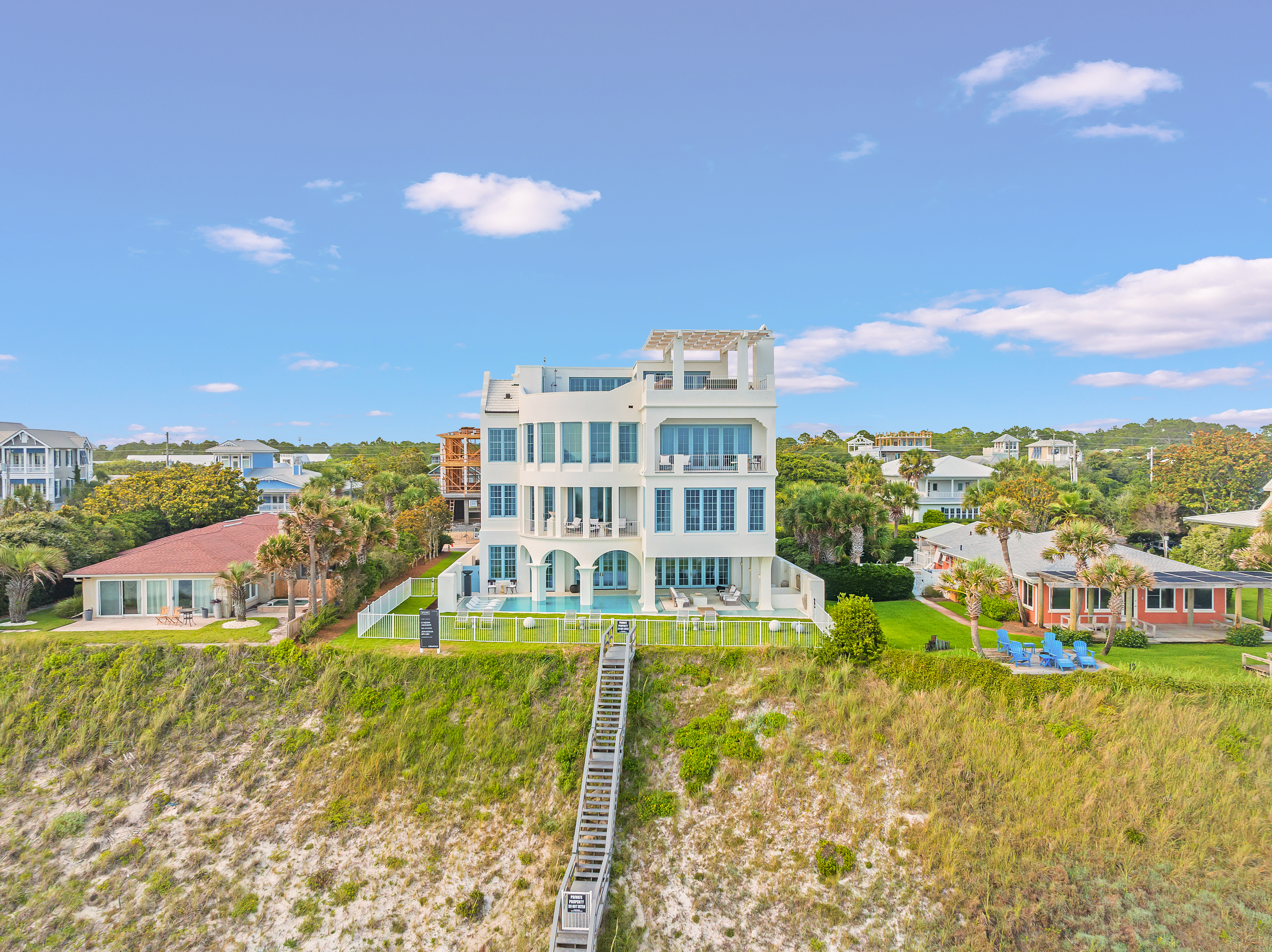 Oceanfront luxury residence overlooking coastal dunes, featuring multiple terraces, expansive windows, and private beach access.