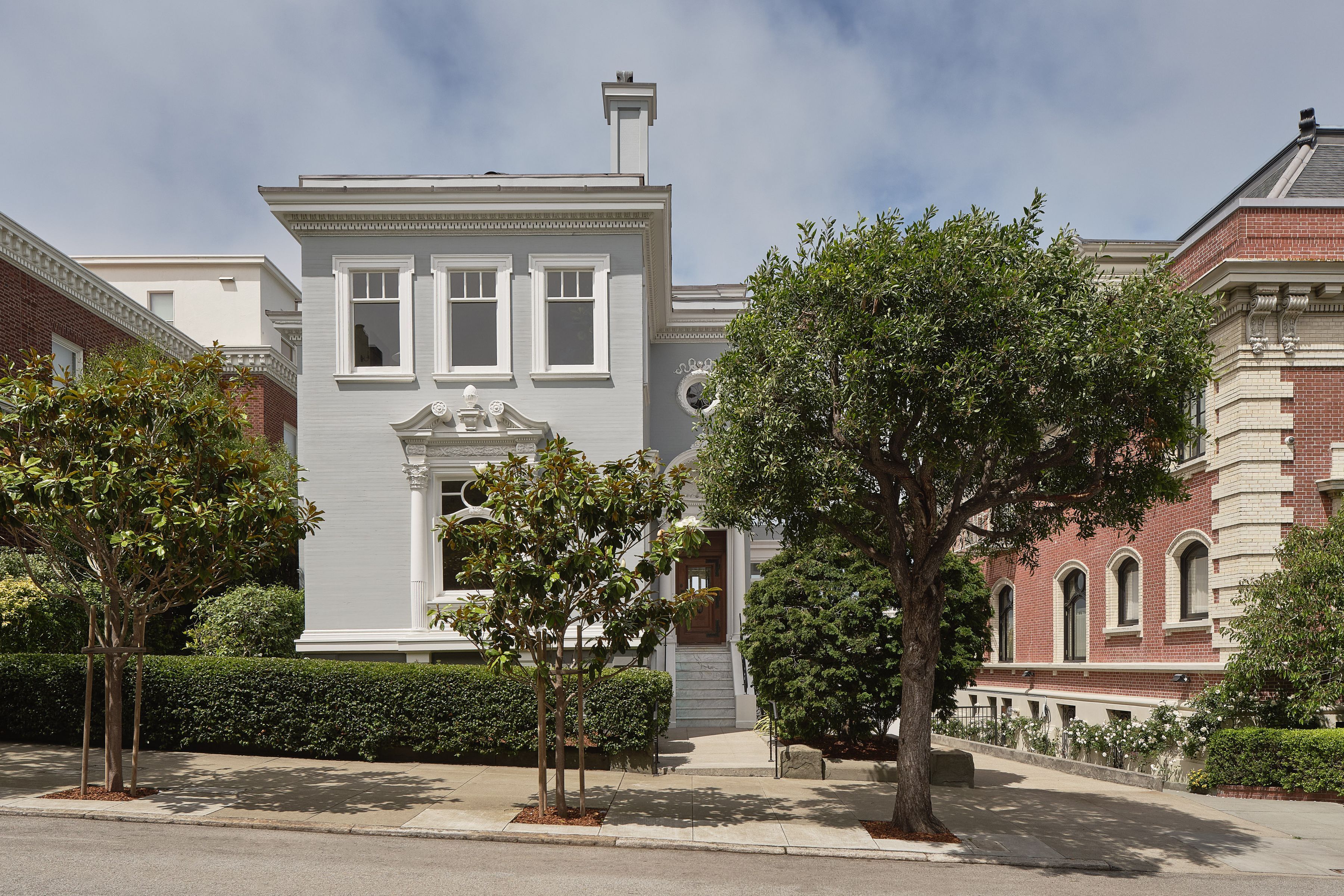 exterior of Presidio Heights home with grey stucco walls and intricate white molding around the windows, and treelined streets